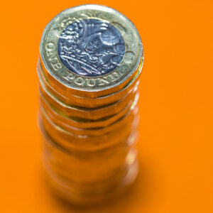 Stack of £1 coins on an orange background