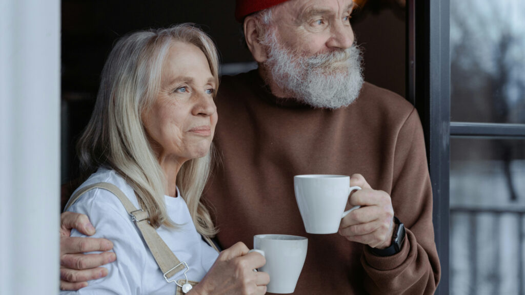 Two people with hot drinks looking to the distance